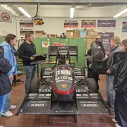 Die Teilnehmerinnen stehen in der Werkstatt des Formula Student Teams und betrachten das Rennauto Sandy