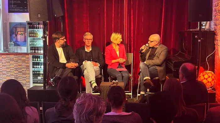 Prof. Daniel Seiberts, Prof. Georg Ebbing, Moderatorin Prof. Dr. Jessica Einspänner-Pflock, und Prof. Volker Kleinekort auf dem Podium bei HSRM-Dialog im ZR6