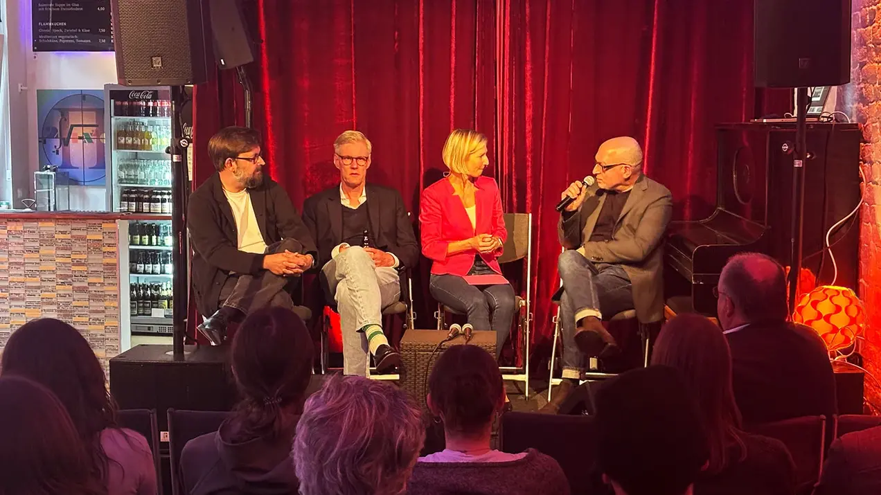 Prof. Daniel Seiberts, Prof. Georg Ebbing, Moderatorin Prof. Dr. Jessica Einspänner-Pflock, und Prof. Volker Kleinekort auf dem Podium bei HSRM-Dialog im ZR6