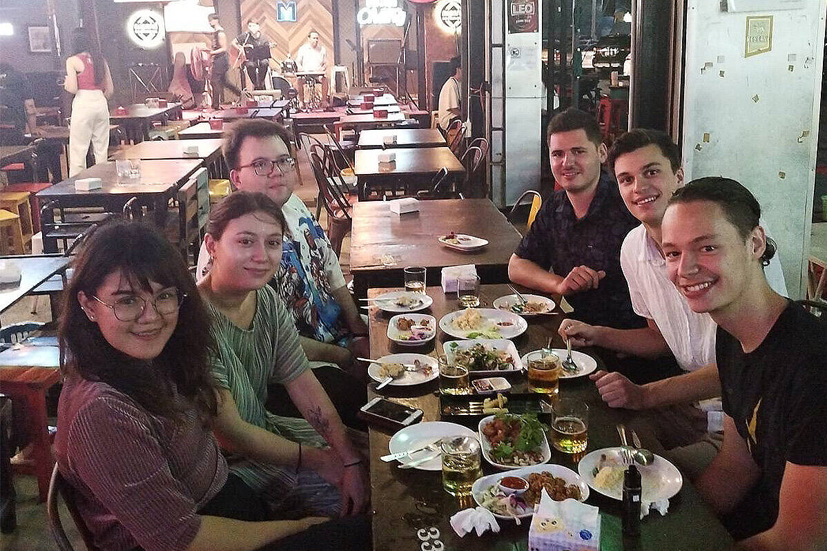 Justus Hamberger  sitzt mit Kommiliton:innen an einem Tisch in einem Restaurant
