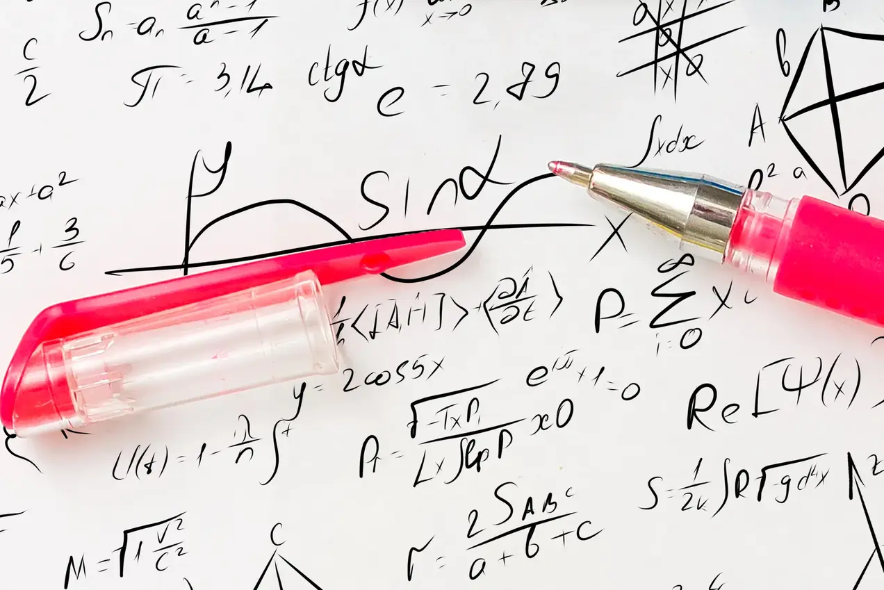 Ein magentafarbener Kugelschreiber liegt auf einem Blatt mit handgeschriebenen mathematischen Formeln, Gleichungen und geometrischen Zeichnungen.