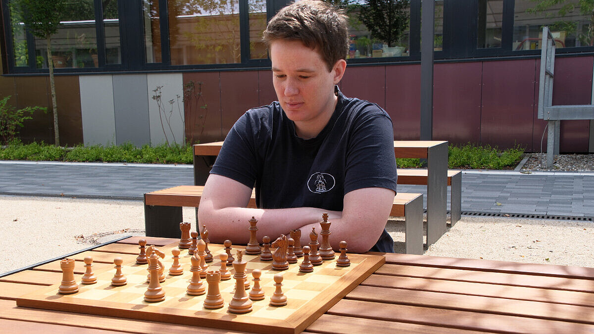 Spitzensportlerin im Schach Anne Lukas Anne Lukas sitzt an einem Tisch auf dem Campus und blickt auf ein Schachbrett, welches vor ihr auf dem Tisch liegt