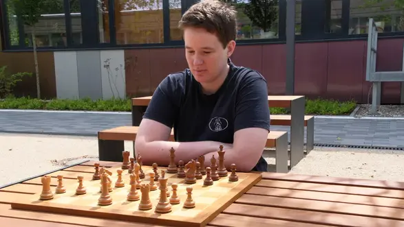 Spitzensportlerin im Schach Anne Lukas Anne Lukas sitzt an einem Tisch auf dem Campus und blickt auf ein Schachbrett, welches vor ihr auf dem Tisch liegt