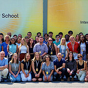 Gruppenfoto mit allen Beteiligten vor einer Werbeplakatwand für die Summer School.