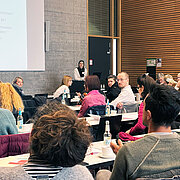 Die Teilnehmenden des Workshops sitzen in einem Saal an langen Tischreihen 