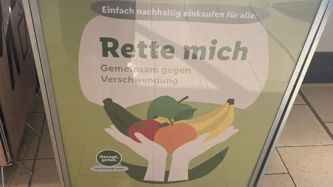 A shopping cart labeled “Save me – Together against waste,” featuring fruit in hands, promoting sustainable shopping to reduce food waste.