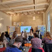 Die Teilnehmer:innen der Auftaktveranstaltung sitzen im Heimathafen im Alten Gericht in Wiesbaden und hören einem Vortrag zu.