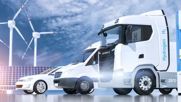 E-Lkw, E-Transporter und E-Pkw mit Windrädern und Photovoltaik im Hintergrund