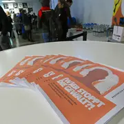 Auf einem Tisch liegen Flyer der Wanderausstellung „(W)er stoppt die Gewalt?!“.