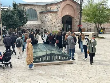 A group of people are standing in a courtyard around a glass floor that may reveal an archaeological find. This is the workshop of the UNESCO Chair at RheinMain University of Applied Sciences and Arts in Bursa.