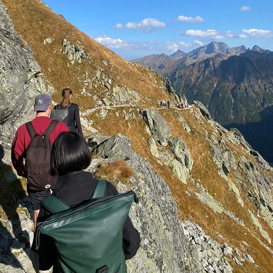 Drei Menschen besteigen einen Berg