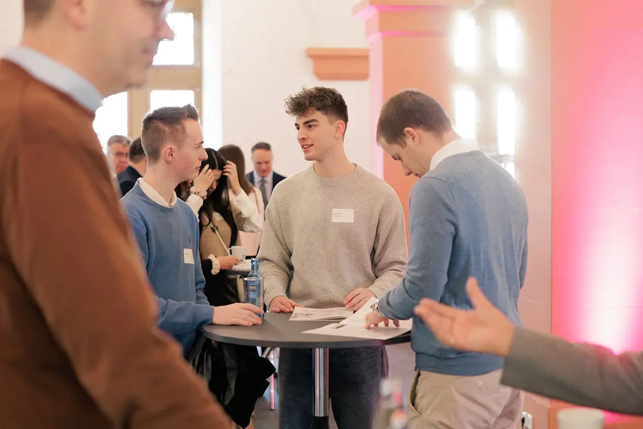 Teilnehmer des Gründungsmarkts stehen an einem Stehtisch und unterhalten sich.