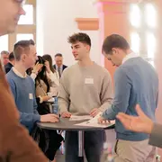 Teilnehmer des Gründungsmarkts stehen an einem Stehtisch und unterhalten sich.