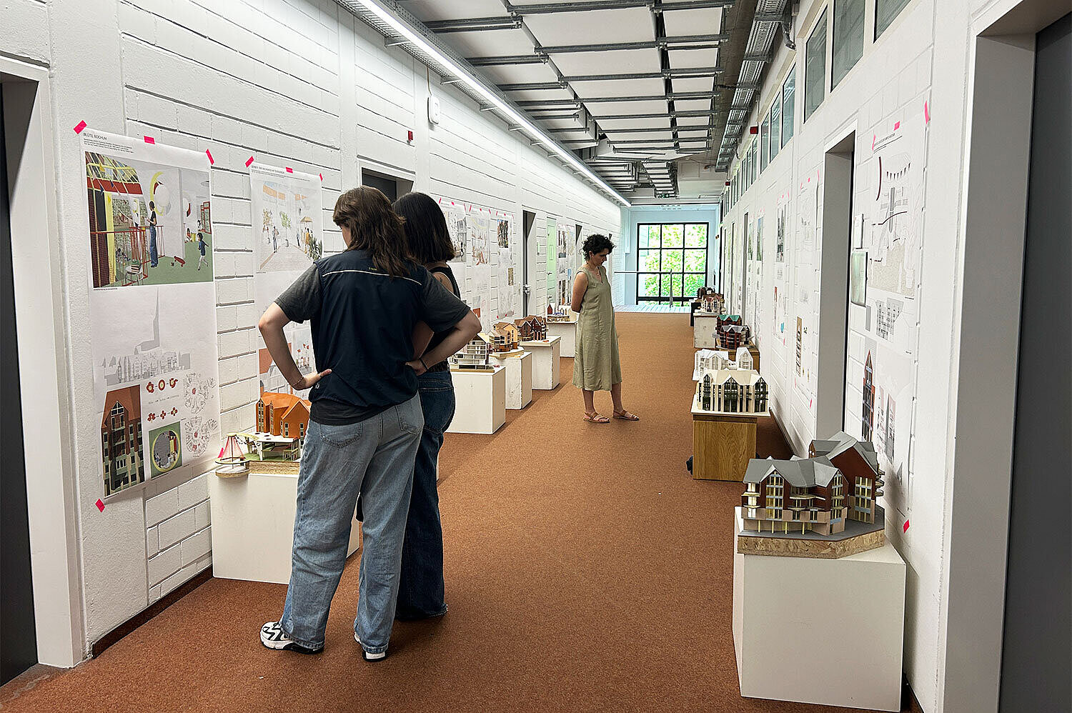 Besucher:innen der Ausstellung betrachten die Entwürfe.