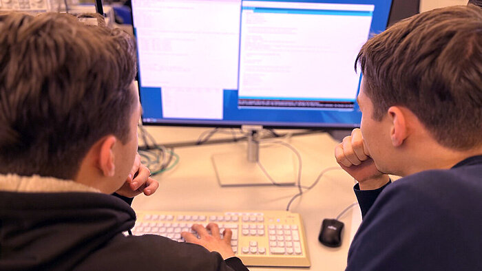 Zwei Schüler sitzen vor einem PC.