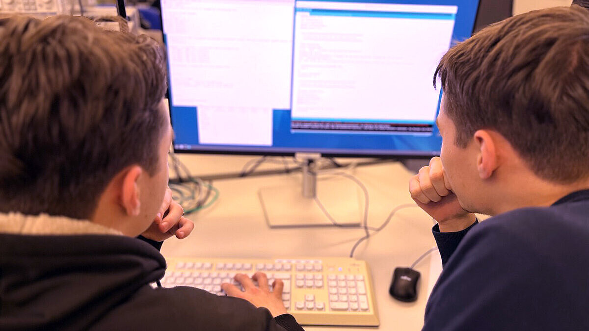 Zwei Schüler sitzen vor einem PC.