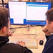 Zwei Schüler sitzen vor einem PC.