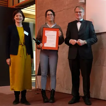 Mia Sophie Schirmmann erhielt eine Anerkennung der Aareal Bank für die drittbeste Bachelor-Arbeit. Sie steht in der Mitte und hält ihren Preis in den Händen , links steht Dr. Kirsten Appel und rechts Prof. Leo Cremer.