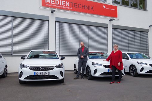 Prof. Dr. Eva Waller, Präsidentin der Hochschule RheinMain, und Dr. Martin Lommel, Kanzler der Hochschule RheinMain mit den neuen E-Fahrzeugen auf dem Campus Unter den Eichen.