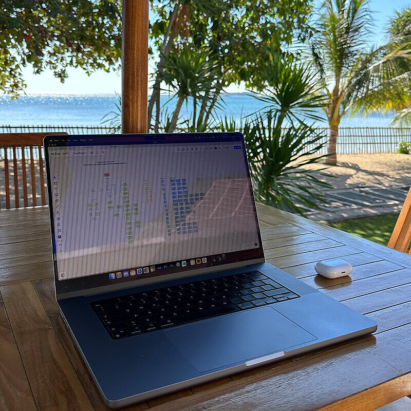 Auf einem Tisch am Strand steht ein Laptop