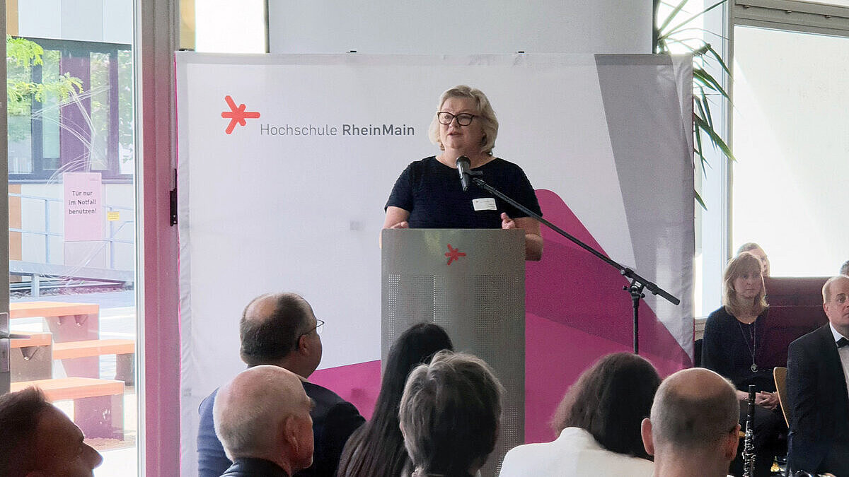 Hochschulpräsidentin Prof. Dr. Eva Waller steht am Rednerpult und spricht zum Publikum