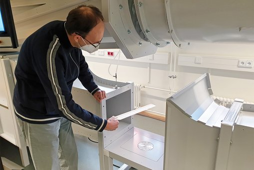 Prof. Dr. Björn-Christian Will hält das Modell eines Tragflügels in den Windkanal