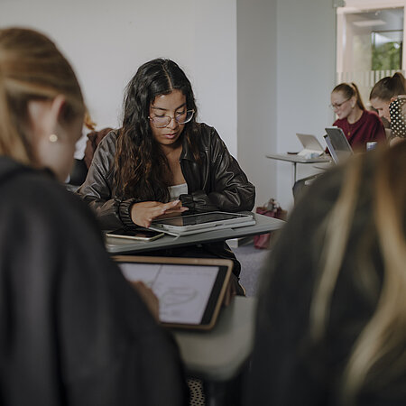 Man sieht viele Studierende, die alle an ihrem Tablet etwas durchlesen oder bearbeiten.