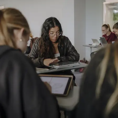 Man sieht viele Studierende, die alle an ihrem Tablet etwas durchlesen oder bearbeiten.