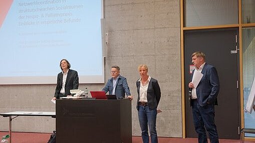 Vier Personen halten einen Vortrag 