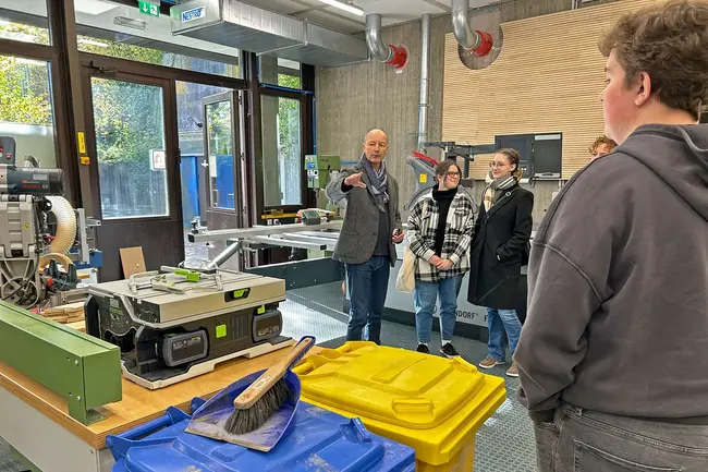 Architekt Prof. Dieter Müller zeigt einer Gruppe von Schüler:innen die Modellbauwerkstatt der Hochschule RheinMain.