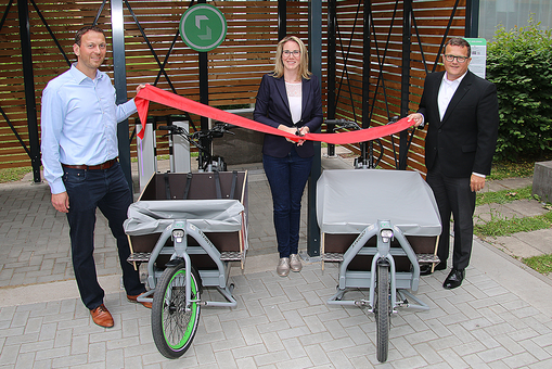 Philipp Harter (sigo GmbH), Sina Jansohn und Holger Lack (beide NHW) nehmen die Lastenrad-Station in Frankfurt-Niederrad in Betrieb