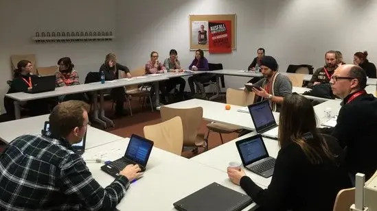 Eine Gruppe sitzt in einem Kreis und arbeiten alle an ihren Laptops