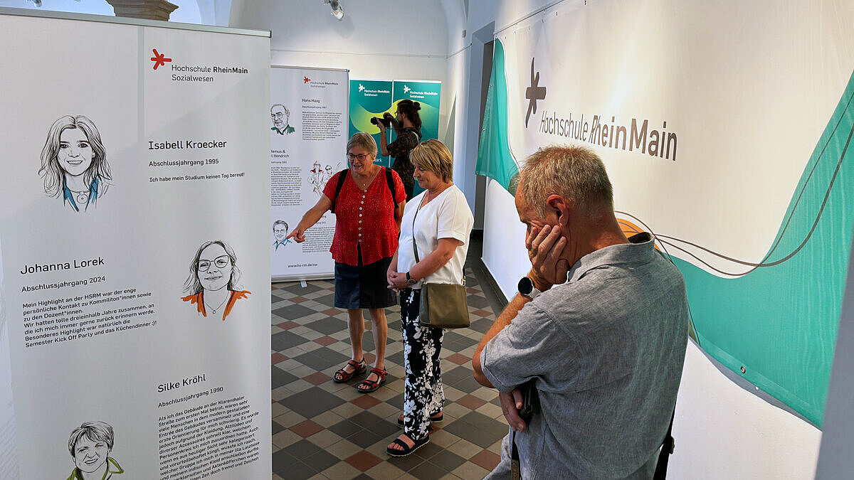 Besucher:innen der Vernissage lesen sich die Informationen auf den Aufstellern durch