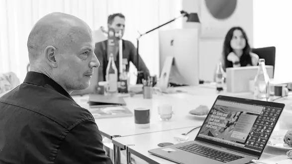 Prof. Jörg Waldschütz sitzt während eines Arbeitstreffens des CCI-Instituts vor seinem Laptop. Im Hintergrund sind zwei weitere Personen zu sehen.