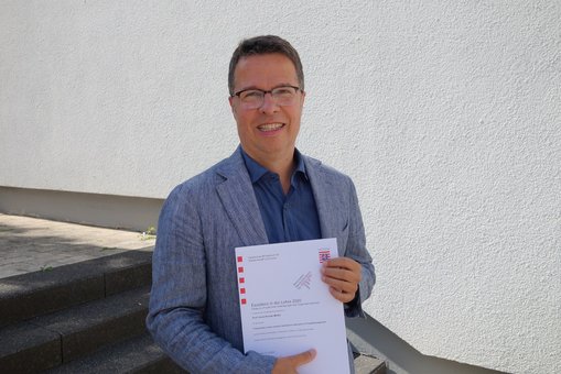 Prof. Roman-Müller mit der Urkunde des HMWK © Hochschulkommunikation | Hochschule RheinMain 