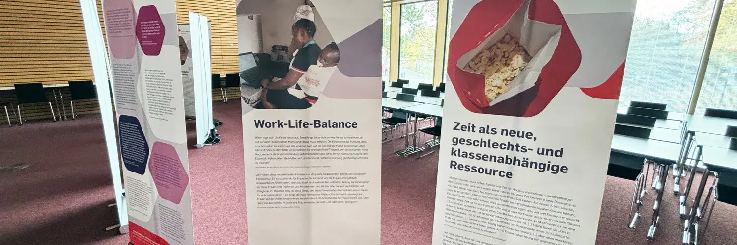 Drei Roll-ups stehen in einem Raum. Sie behandeln Themen wie Work-Life-Balance und gesellschaftliche Ressourcen. Die Schriftzüge sind gut lesbar und enthalten informative Texte über die entsprechenden Themen. Der Raum ist modern und hat große Fenster, die Tageslicht hereinlassen.