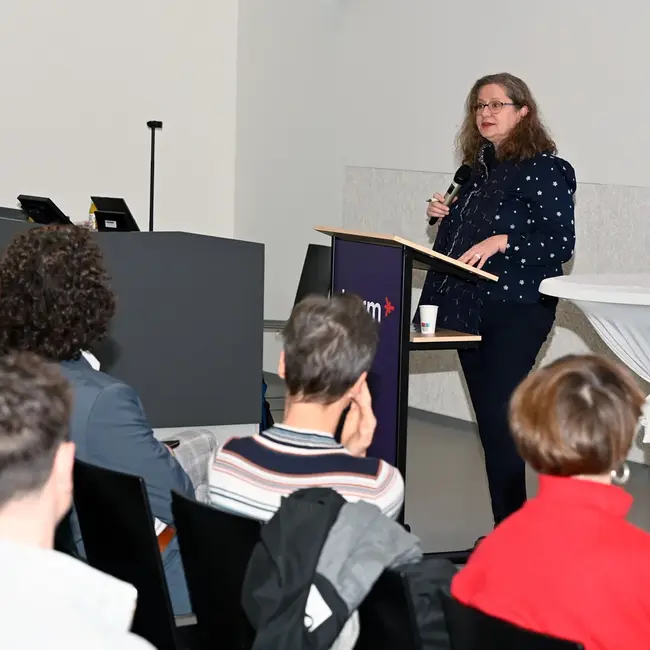 Nicola Müller, Bundesministerium für Wohnen, Stadtentwicklung und Bauwesen, steht hinter einem Rednerpult und hält einen Vortrag beim 2. Wiesbadener Tag für sozial nachhaltiges Investieren an der Hochschule RheinMain.