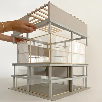 Architekturmodell von Architekturstudentinnen der HSRM aus transparenten Materialien und Holzrahmen, mit mehreren Ebenen und einem flachen Dach. Die Architektur zeigt klare Linien und eine offene Struktur. Es zeigt den Entwurf „Tanzbox Wiesbaden“ von Lena Al Reda und Hannah Eckert.