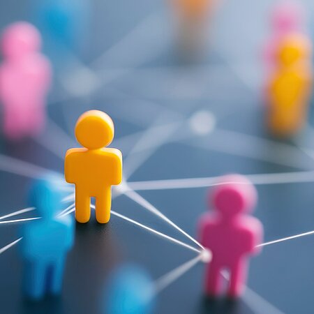 Bunte Spielfiguren auf grauem Hintergrund die über weiße Linien verbunden sind