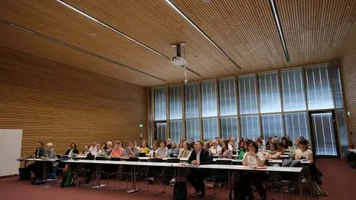 Gruppe sitzt in Reihen in einem Raum
