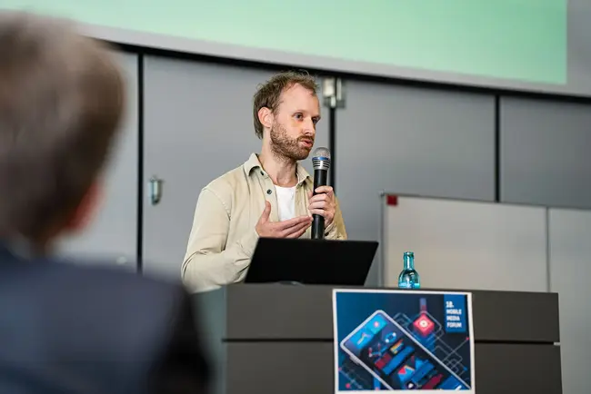 Sebastian Brähler von Kaleidos:Code spricht während seines Vortrags ins Mikrofon.