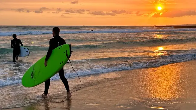 Auslandssemester Eric Bingenheimer Zwei Surfer befinden sich am Strand, während die Sonne untergeht
