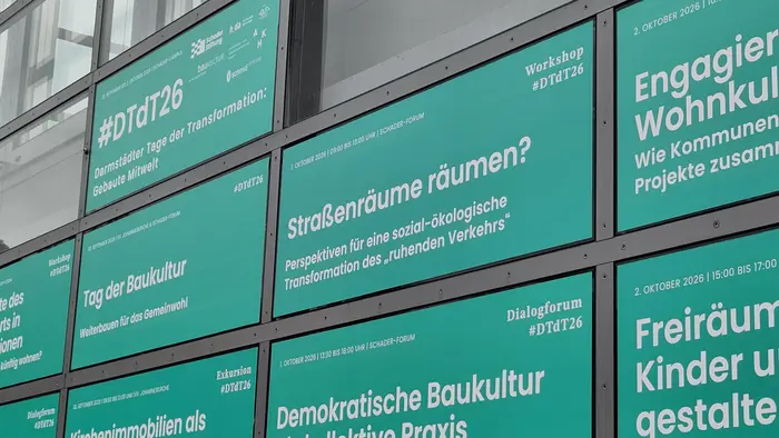 Der Bildinhalt zeigt mehrere grüne Plakatwände mit Texten. Themen umfassen einen Workshop zum #DtD26, die Frage nach der Nutzung von Straßenräumen, und Diskussionen zur Baukultur und sozialen Transformationen. Das Datum und der Titel einer Veranstaltung sind ebenfalls erwähnt.