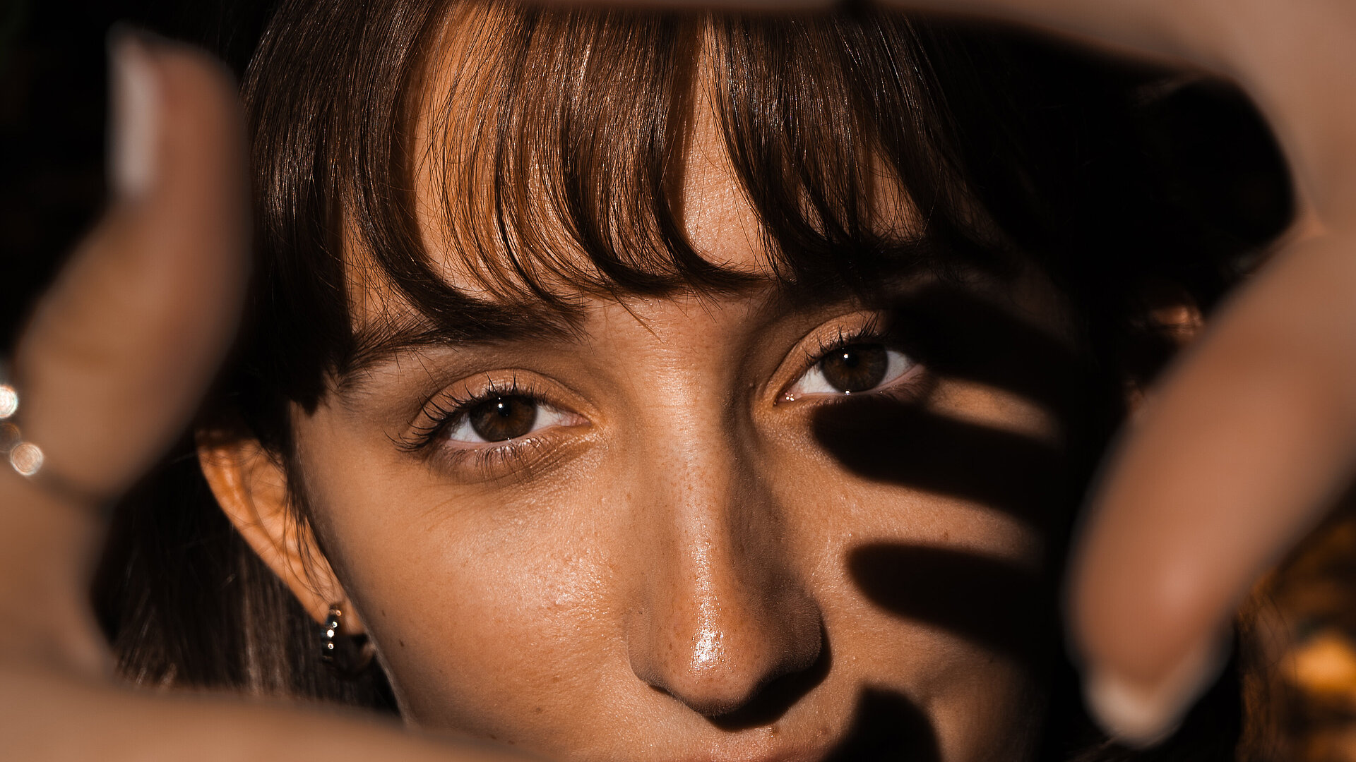 Jana Stiriz Licht und Schatten Eine Frau hält die Finger wie im Viereck vor das Gesicht und spielt so mit Licht und Schatten