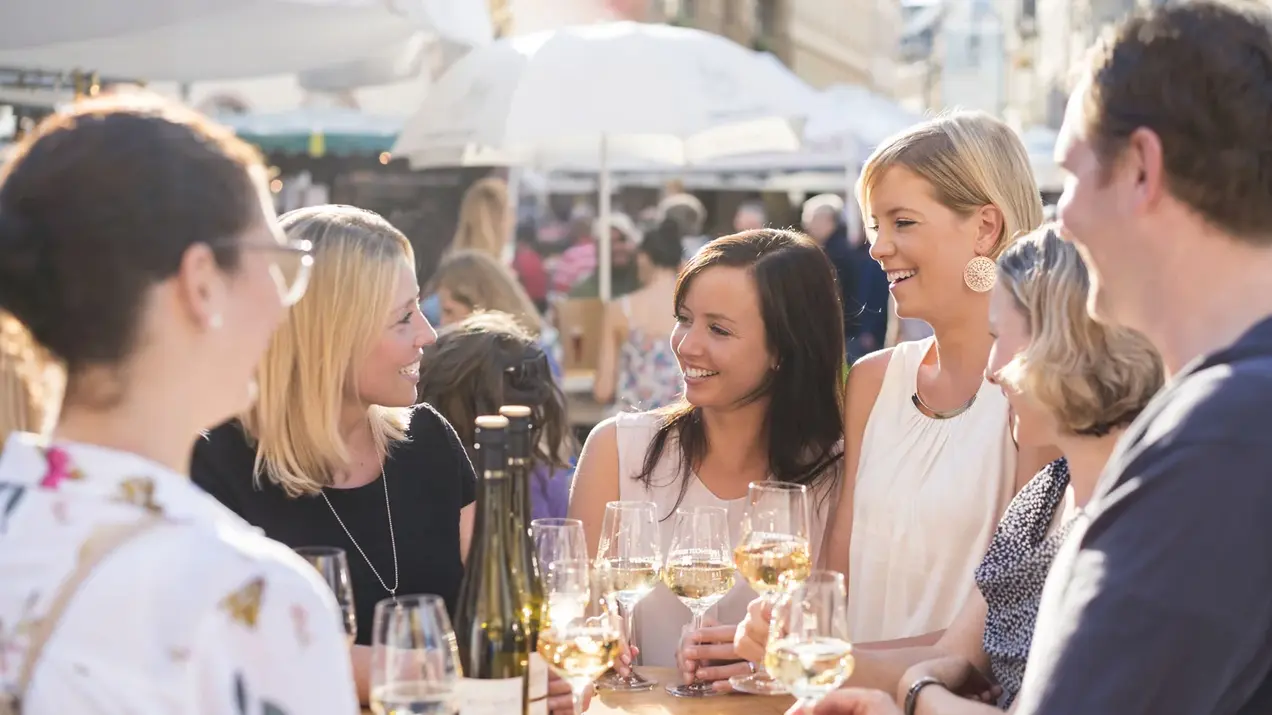 Studierende an einem Stehtisch auf der Rheingauer Weinwoche stoßen mit Weingläsern an