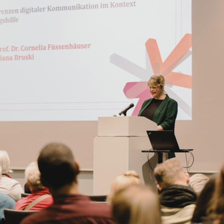 Person am Pult steht vorne und liest Person am Pult steht vorne und liest