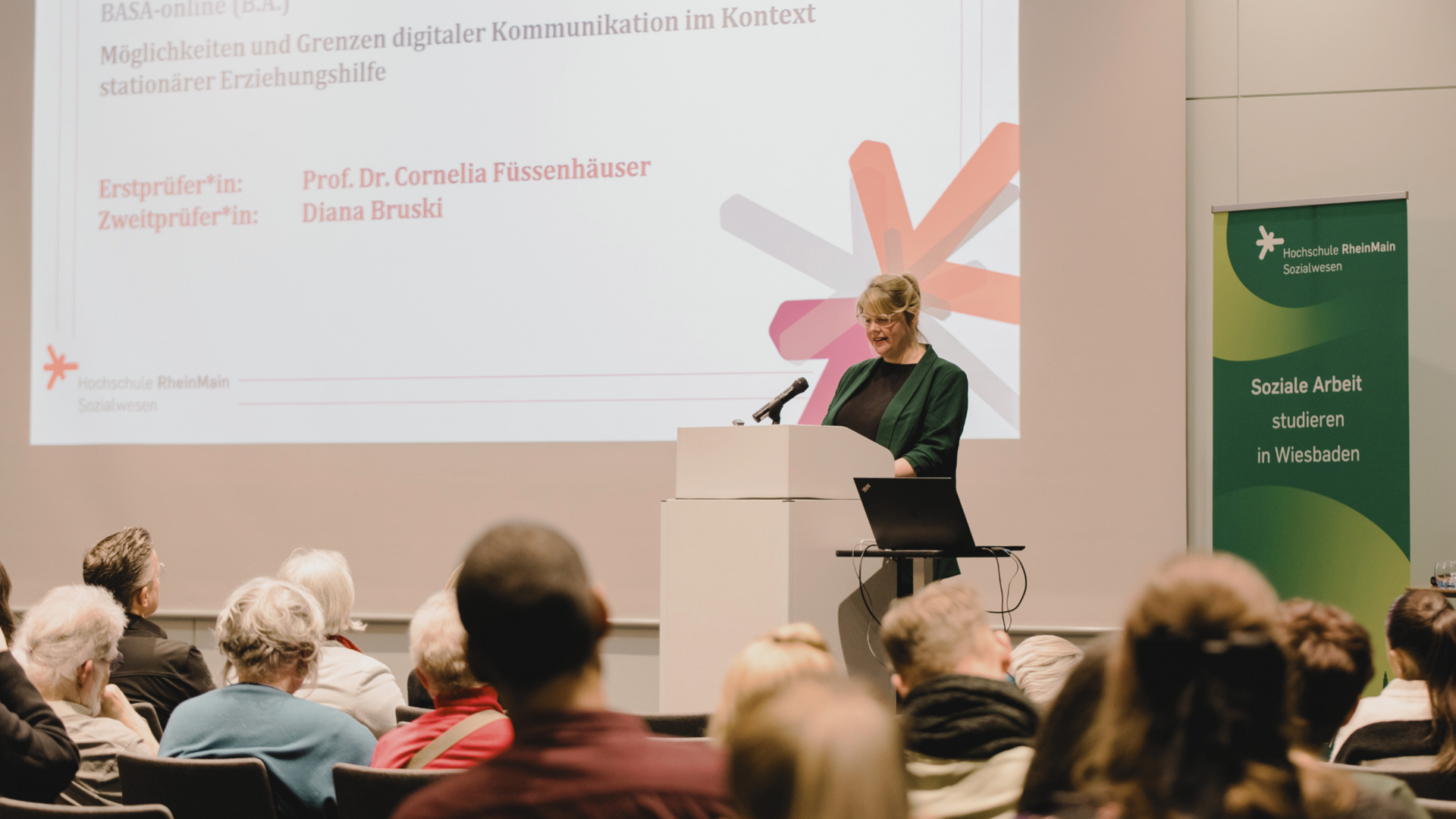 Person am Pult steht vorne und liest Person am Pult steht vorne und liest