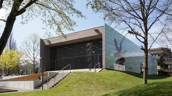 Außenansicht Gebäude G mit Glasfront und großem Hochschullogo auf der Seitenwand