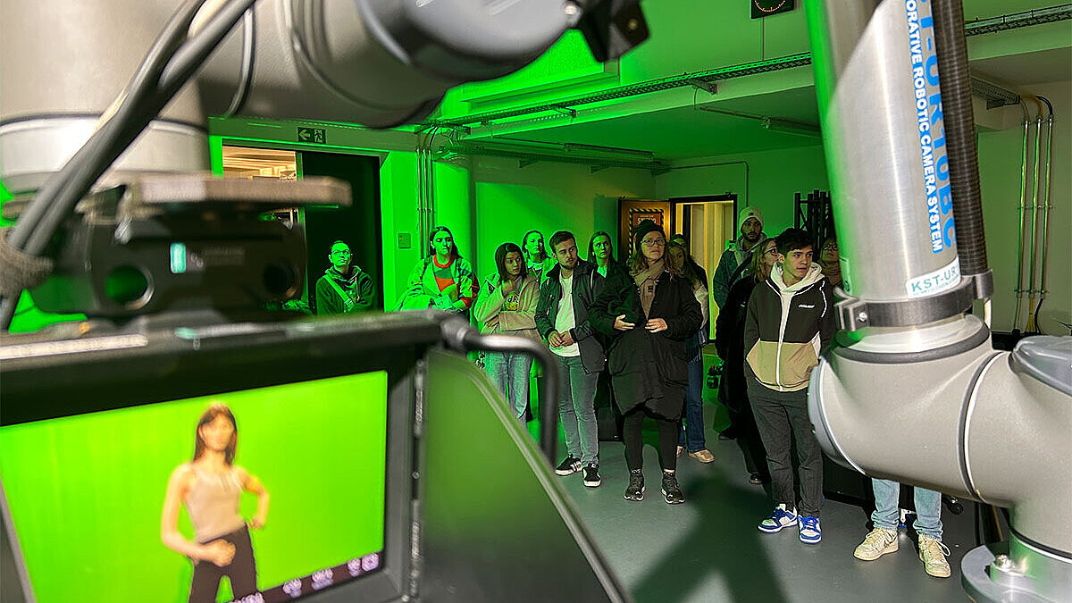 Blick durch den Arm eines Kameraroboters auf Schüler:innen