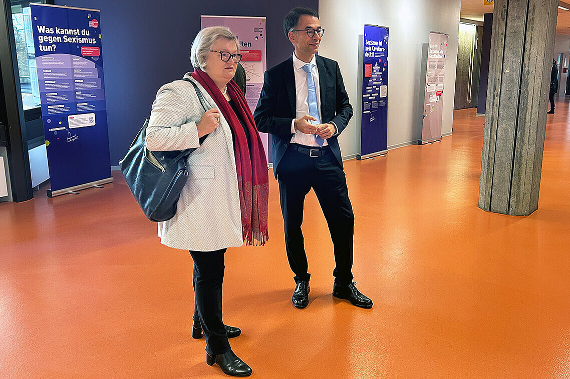 Hochschulpräsidentin Prof. Dr. Eva Waller und der hessische Justizminister Christian Heinz sehen sich gemeinsam die Ausstellung „Gemeinsam gegen Sexismus“ an der Hochschule RheinMain an.